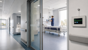 Healthcare isolation room with a wall-mounted critical room pressure monitor beside the doorway
